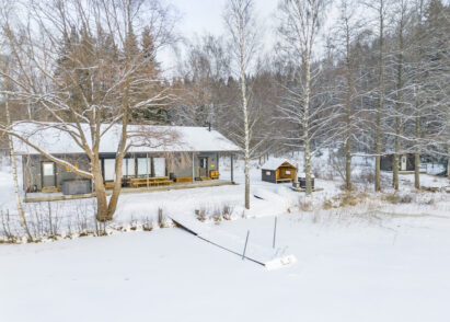 Aulanko Lake Villa in its winter attire. In the center, a covered outdoor fireplace and hot tub; on the right, a separate guest cabin.