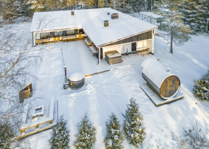 Villa Springrock in its winter attire. Under the canopy is an outdoor jacuzzi; in the foreground an outdoor fireplace, a hot tub, and a wood-heated yard sauna.