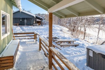 Winter view from the terrace of Aulanko Lakeside's lakefront sauna. In the foreground, there is a wood-heated hot tub, and on the main building's terrace, there is an electric heated jacuzzi.