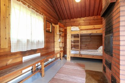 In the dressing room of the larger lakeside sauna at Evo Ruuhijärvi, there is a bunk bed with two sleeping places and a sturdy brick stove.