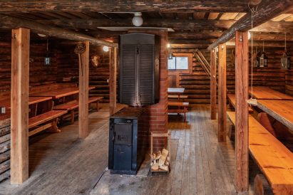The interior of Evo Ruuhijärvi's Event Shed is dominated by cast iron stove and sturdy bench and table sets made from split logs.