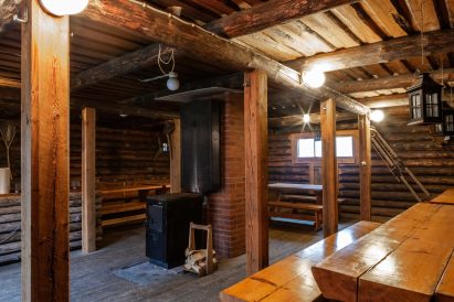 The interior of Evo Ruuhijärvi's Event Shed is dominated by cast iron stove and sturdy bench and table sets made from split logs.