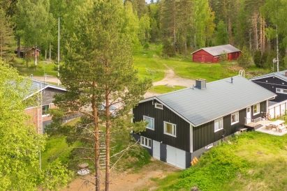 The living room windows of Evo Lakeside Villa, part of Evo Twin, offer a view of Lake Kaitalammi. In the background, the red Evo Wilderness Barn.