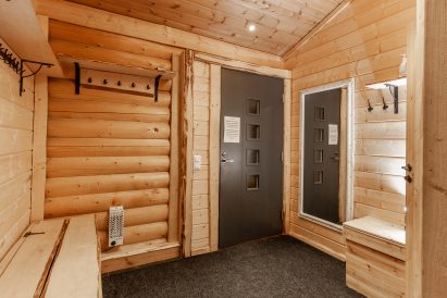 The vestibule and cooling lobby of Loppi Wilderness Villa's indoor sauna, from which there is direct access to the spacious outdoor terrace and the warmth of the hot tubs.