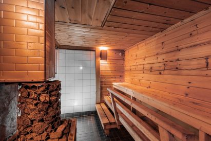 The wood-heated sauna of Loppi Wilderness Villa's Mini Villa has a shower area in the back corner.