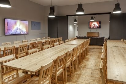 The main hall of Räyskälä Grand Villa features two widescreen televisions and a piano. The arrangement and number of tables can be adjusted according to needs.