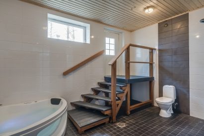The shower room of the electric sauna section on the lower floor of Räyskälä Grand Villa, which also includes a toilet and a jacuzzi. The space provides direct access to the outdoor terrace and the warmth of the hot tubs.