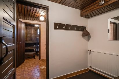 The dressing room of the electrically heated mini-sauna in Räyskälä Grand Villa. In the middle, there is a shower room, and at the back, there is the hot room.